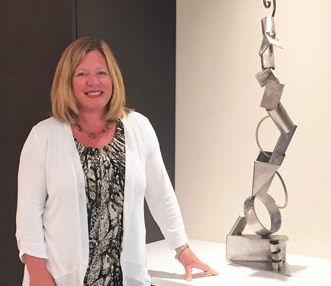 A woman standing in front of a metal sculpture.