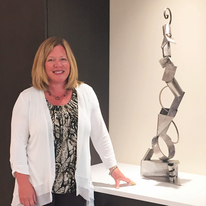 A woman standing in front of a metal sculpture.