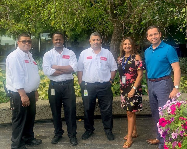 A group of people posing for a photo in front of a flower garden.