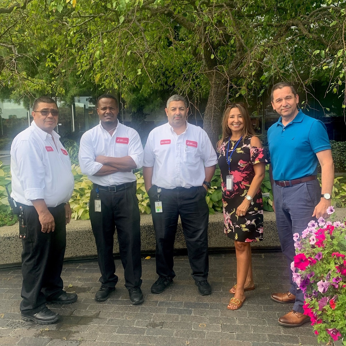 A group of people posing for a photo in front of a flower garden.