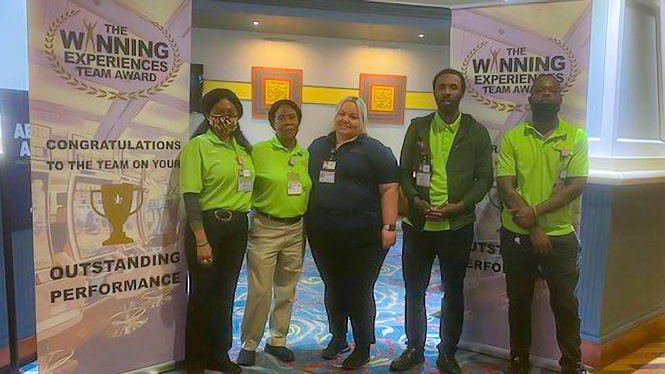 A group of people standing in front of a winning experience banner.