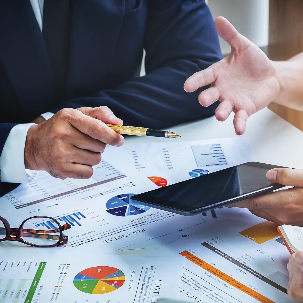 A group of business people sitting around a table with papers and graphs.