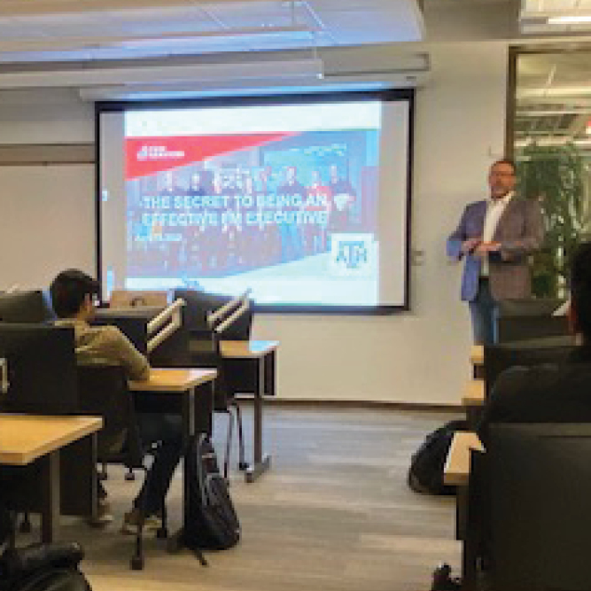 A man giving a presentation to a group of people in a classroom.