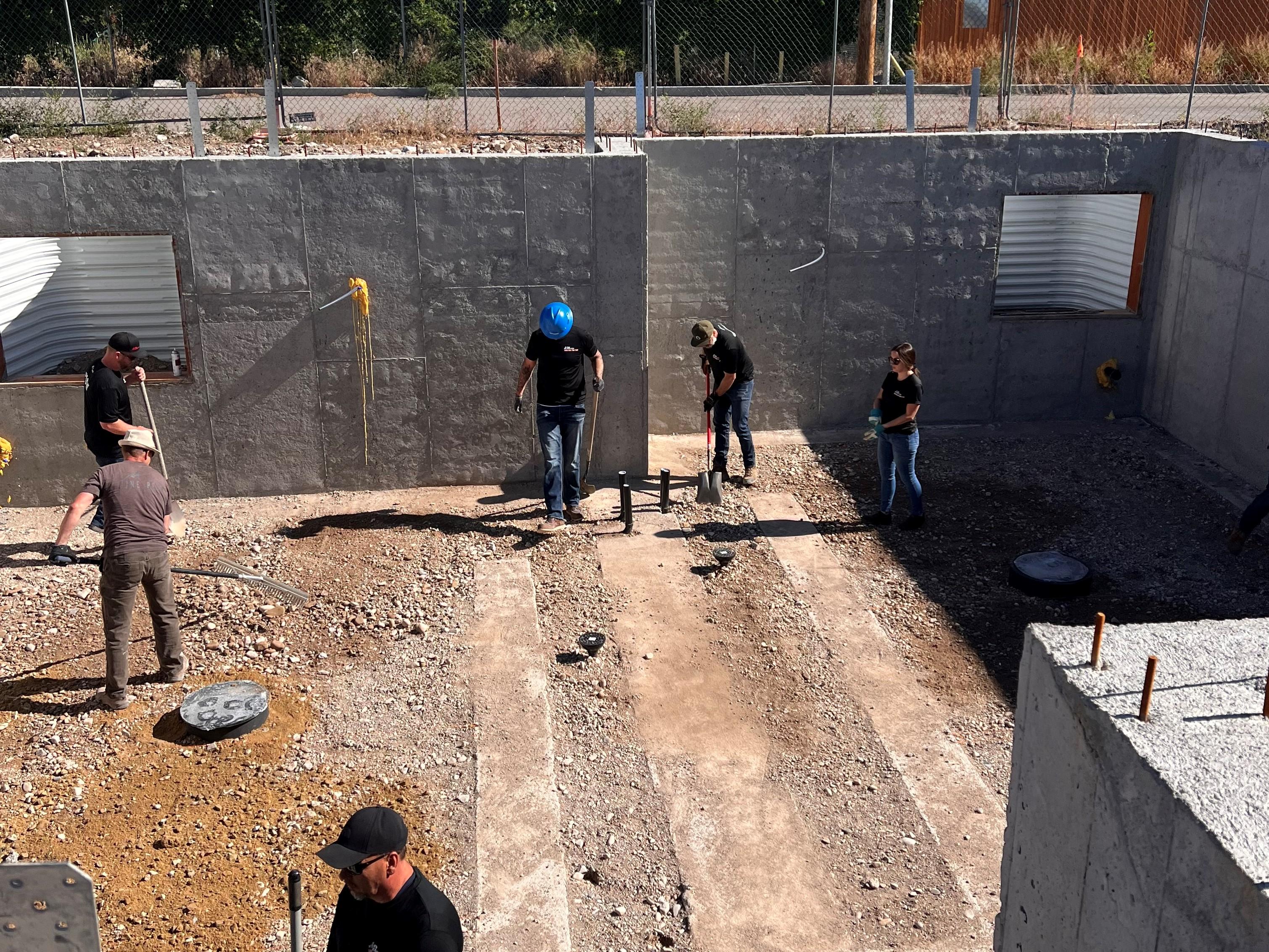 C&W Services volunteers smoothing gravel in preparation for new basement flooring