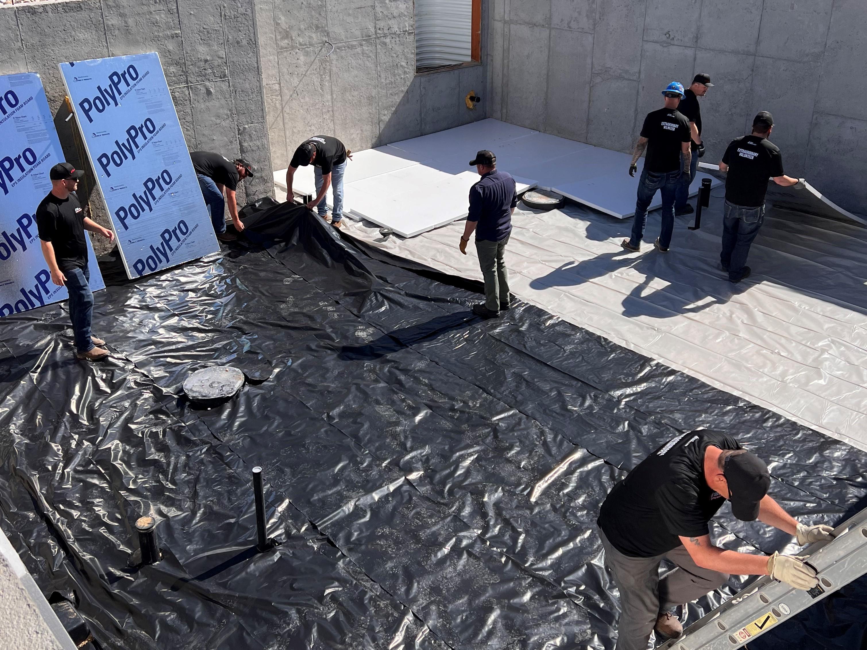 C&W Services volunteers laying down tarp in preparation for new basement flooring