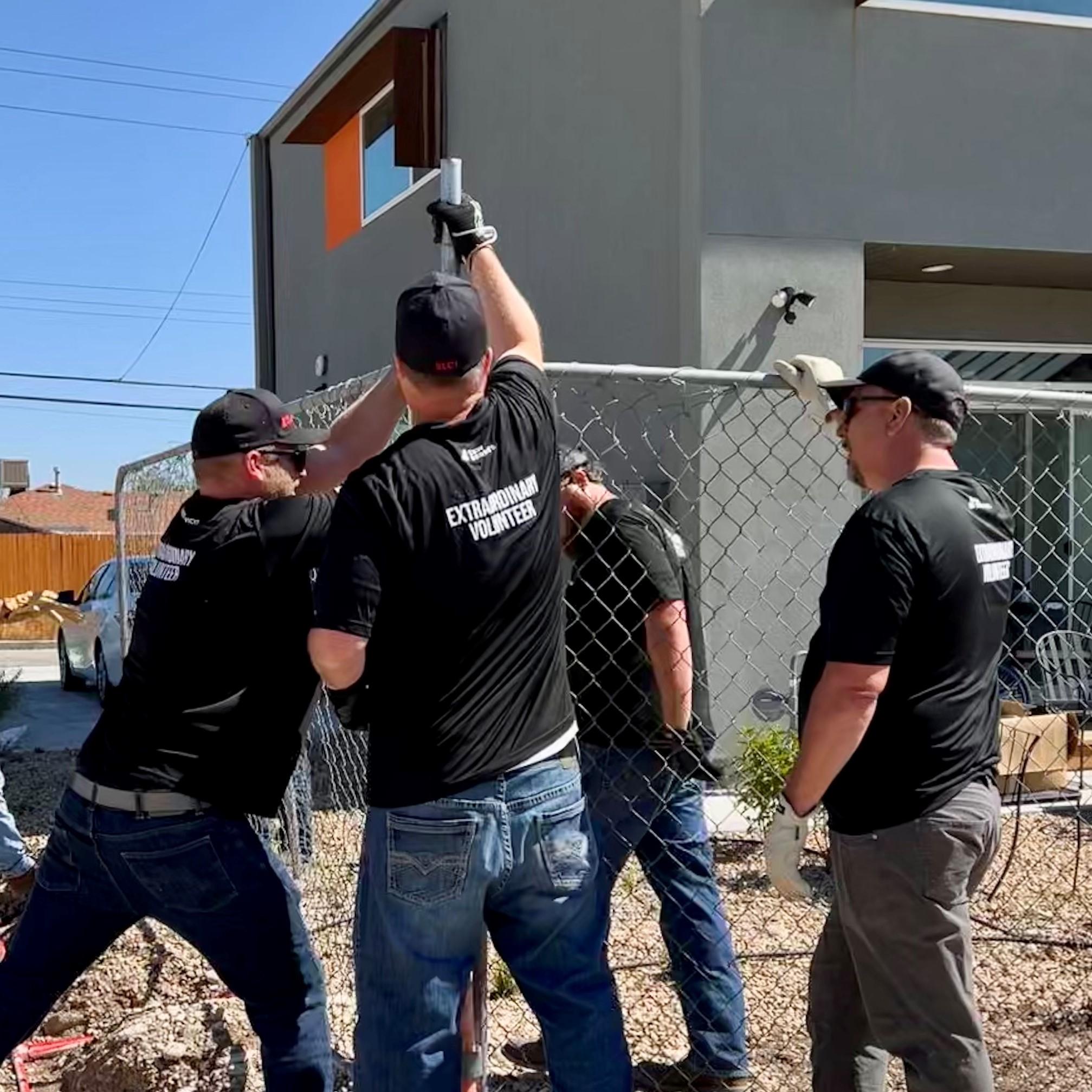 C&W Services employees wearing "Extraordinary Volunteers" tshirts installing a chain link fence fence post