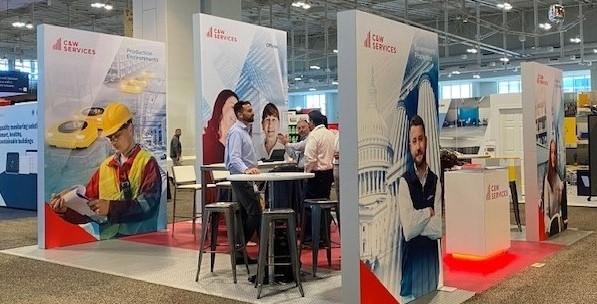 A trade show booth with a lot of people standing around.