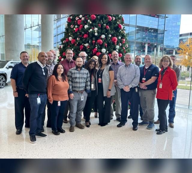 A group of people standing in front of a christmas tree.