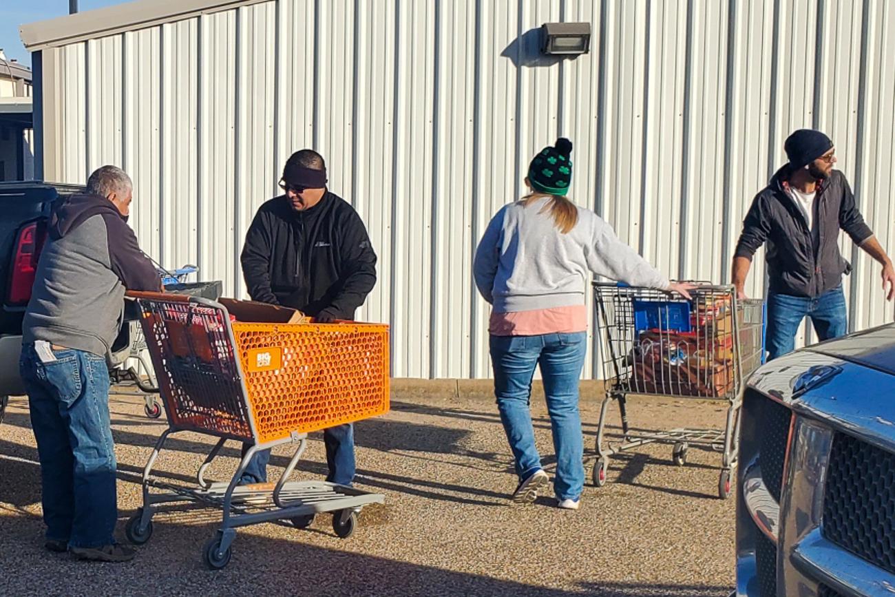 A group of people with shopping carts in front of a building.