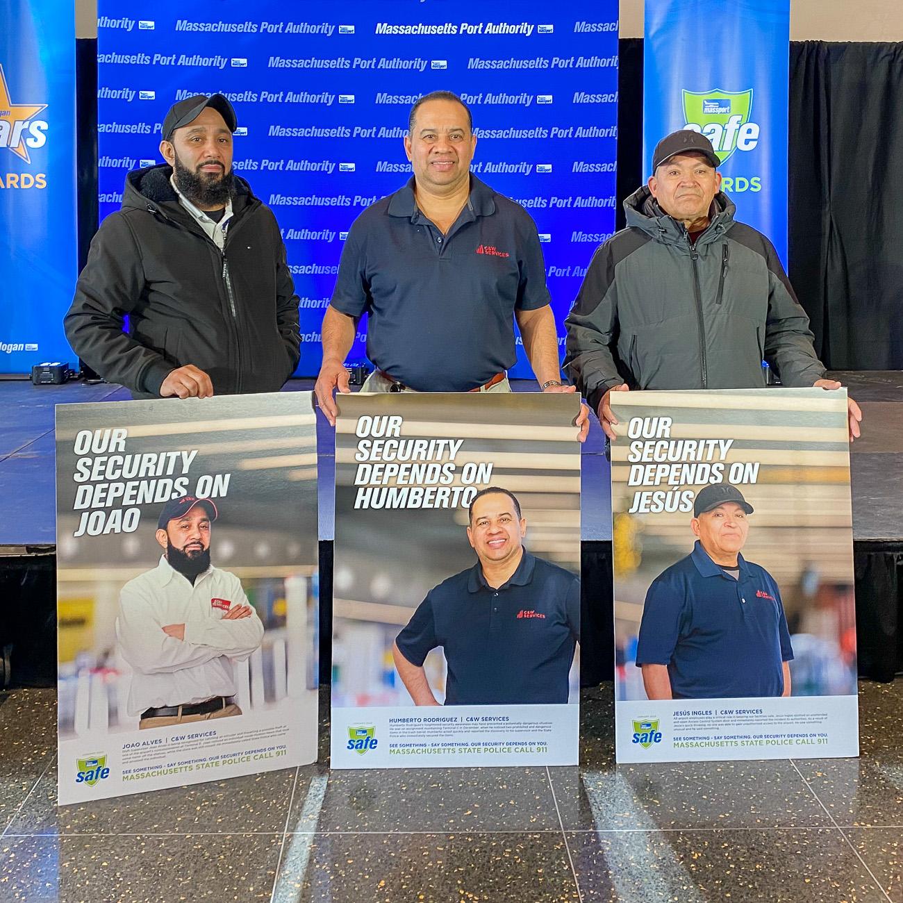 Three men standing with posters in front of them.