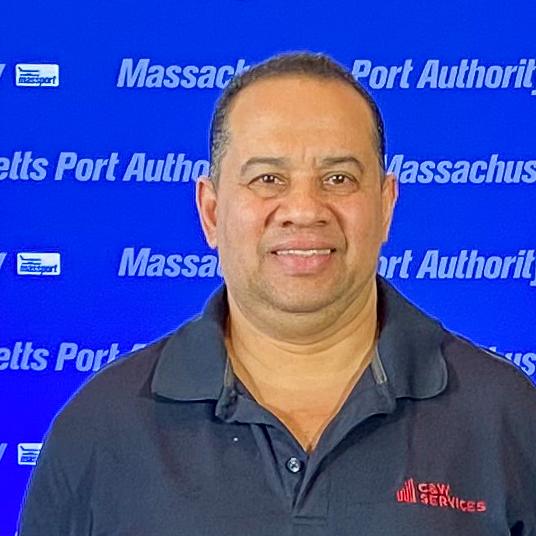 A man in a black shirt standing in front of a blue background.