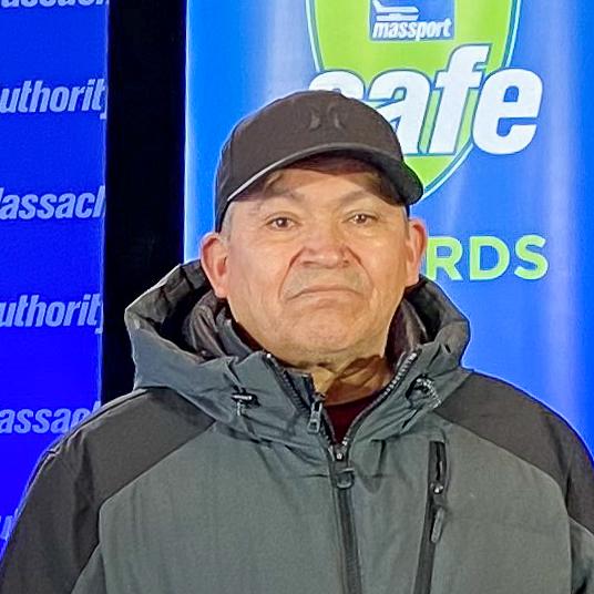 A man in a jacket standing in front of a safe awards banner.