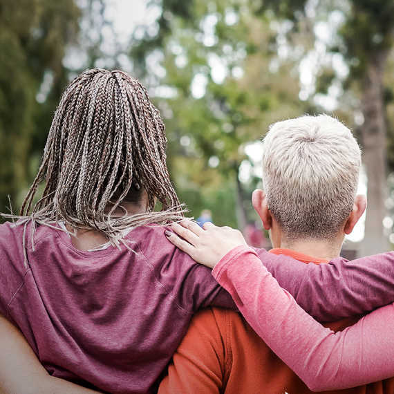 Women with their arms around each others' shoulders.