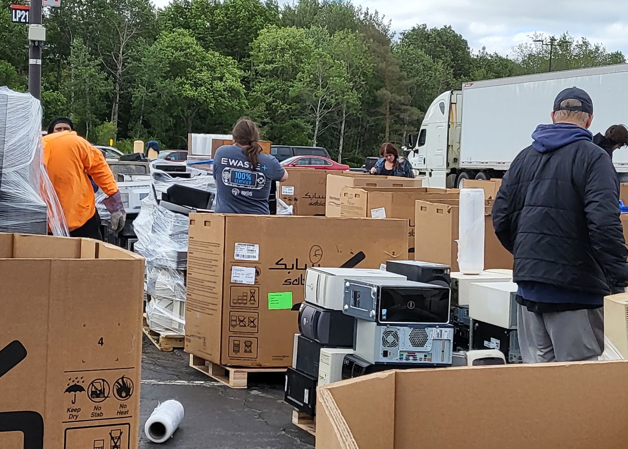 A group of people standing in a parking lot with boxes.