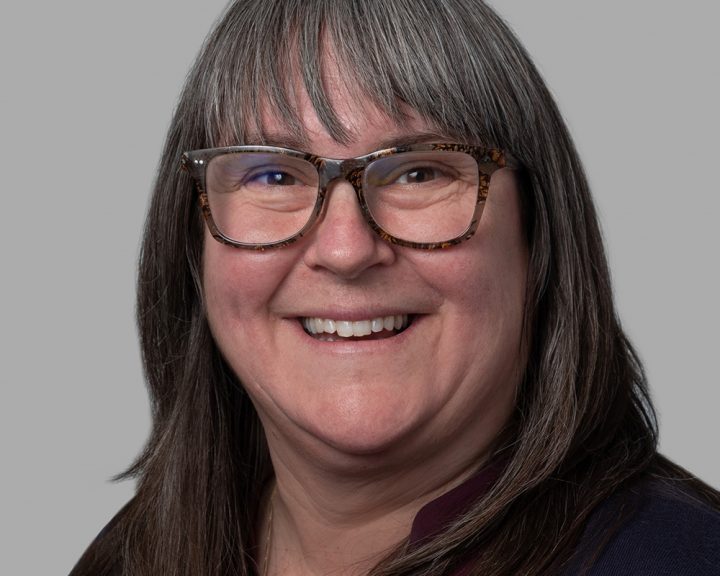 A woman with glasses smiling for the camera.