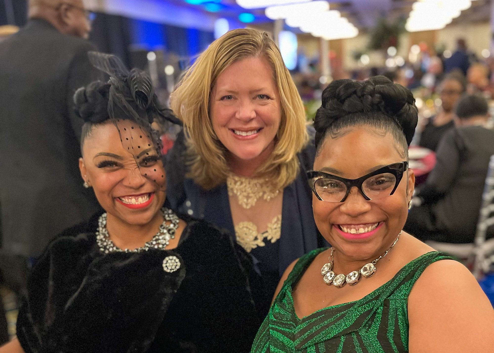 Three women posing for a photo at an event.
