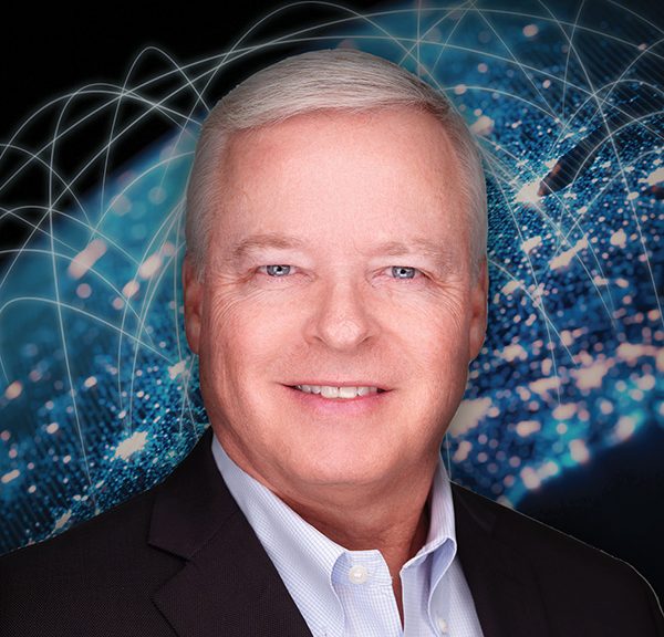 A man in a suit and tie smiling in front of a globe.