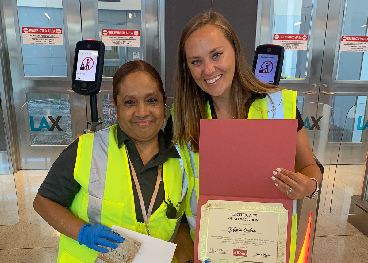 Two smiling women wearing safety vests with their arms around each others' shoulders