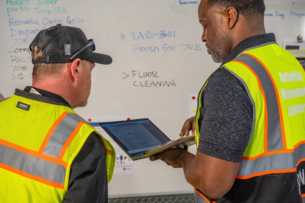 Men in reflective vests looking at a computer