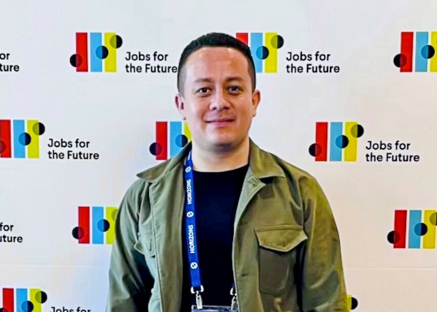 A man standing in front of a wall with Jobs for the Future logos