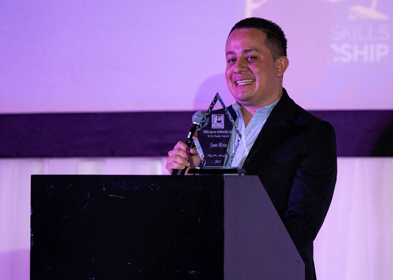 A man standing at a podium holding an award.
