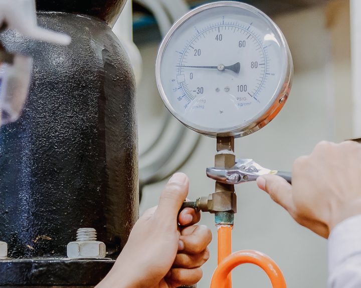 Engineer checking Condenser Water pump and pressure gauge with wrench.