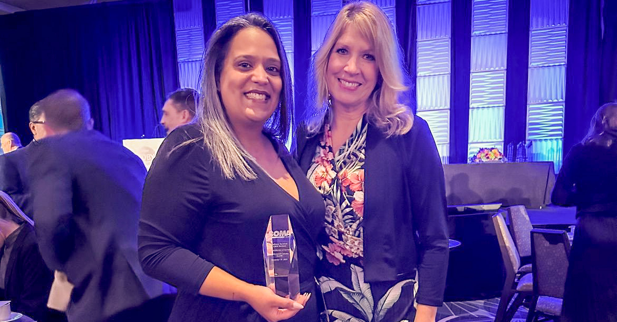 Two women standing next to each other holding an award.