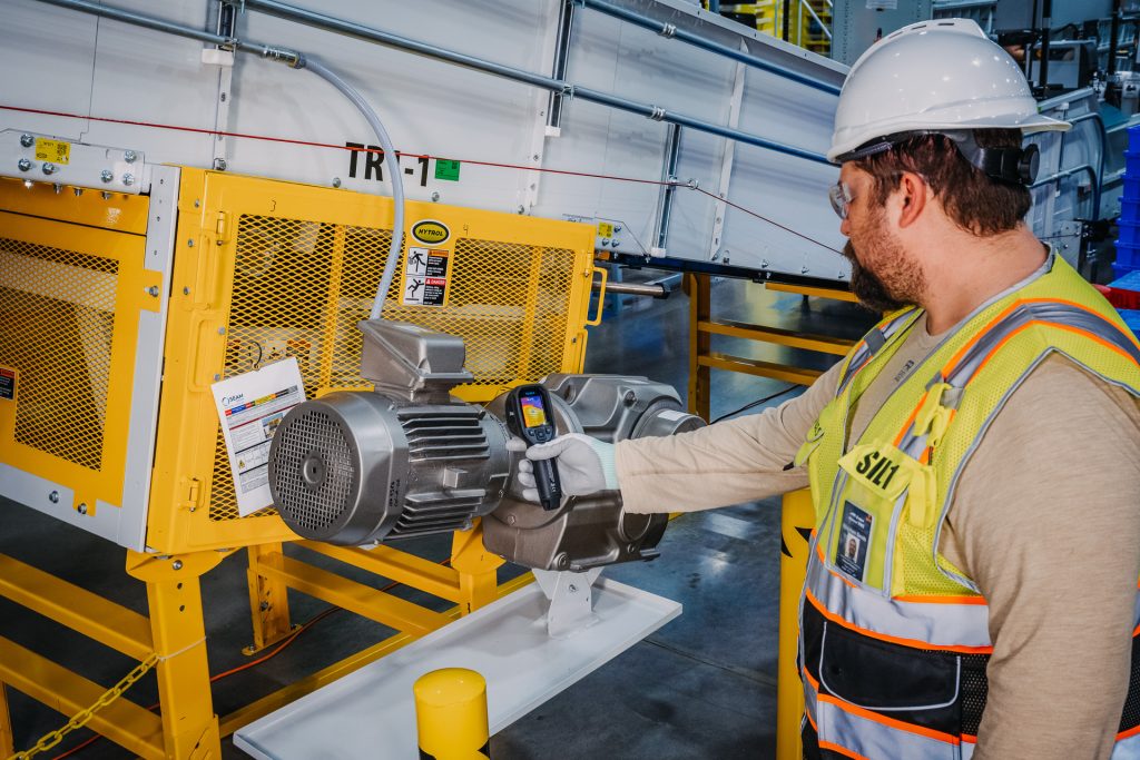 A man in a safety vest and hard hat working on a machine.