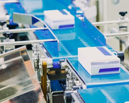 A line of blue boxes on a conveyor belt in a factory.