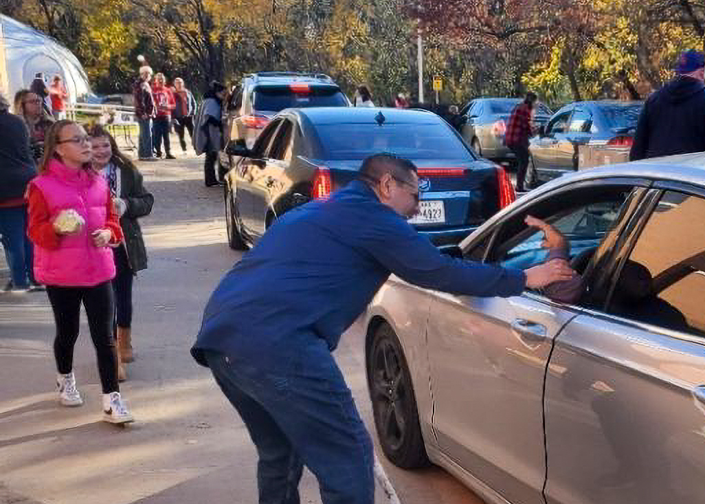 A man is talking to driver in a car.