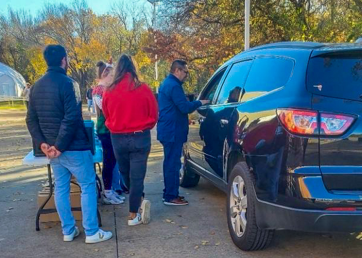 A group of people standing next to a black SUV.