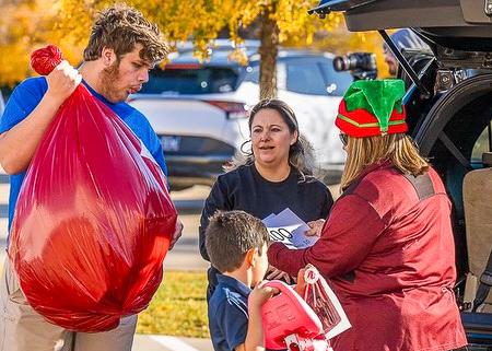 A group of people putting gifts in the trunk of a car.